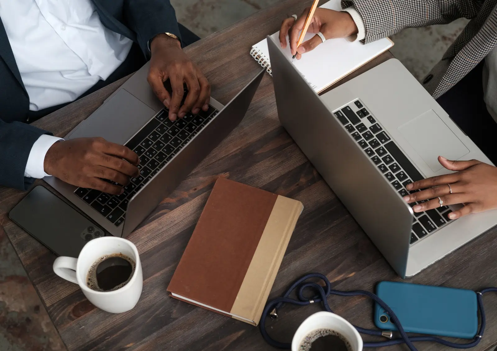 Deux collaborateurs travaillent sur leurs ordinateurs et prennent des notes